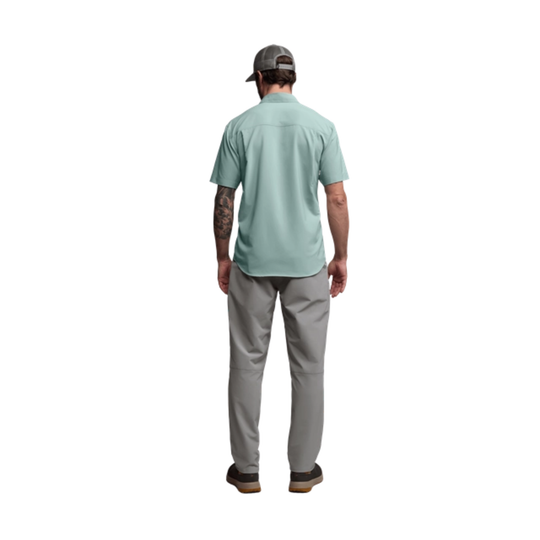 Man wearing a light green shirt and gray pants on a white background