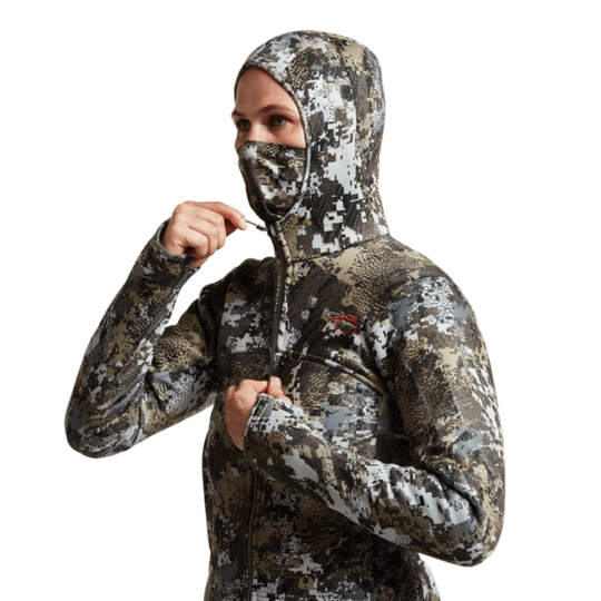 Person wearing a digital camouflage hoodie and face mask on a white background