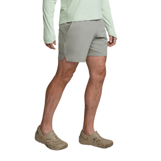 Person wearing light green long-sleeve shirt, gray shorts, and beige Crocs on a white background