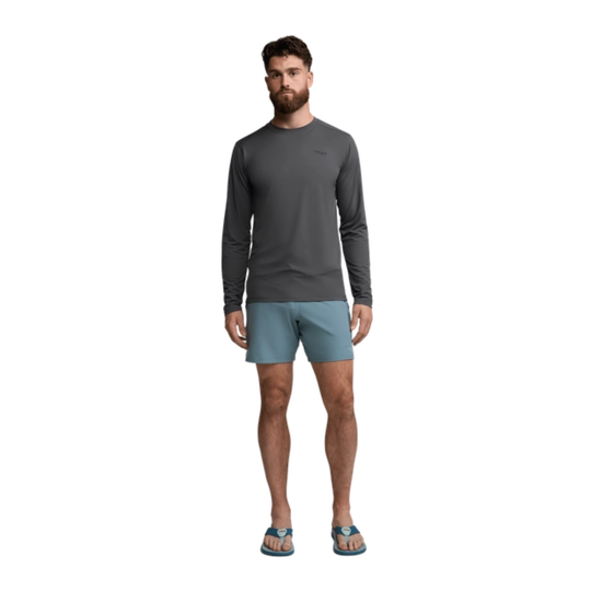 Man wearing a gray long-sleeve shirt and light blue shorts on a white background