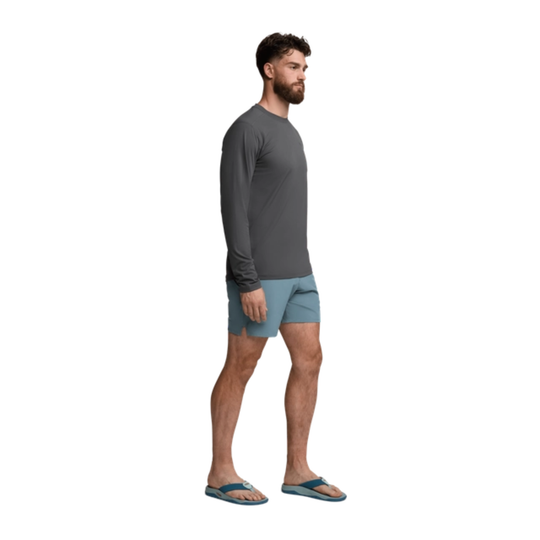 Man wearing a gray long-sleeve shirt and light blue shorts on a white background