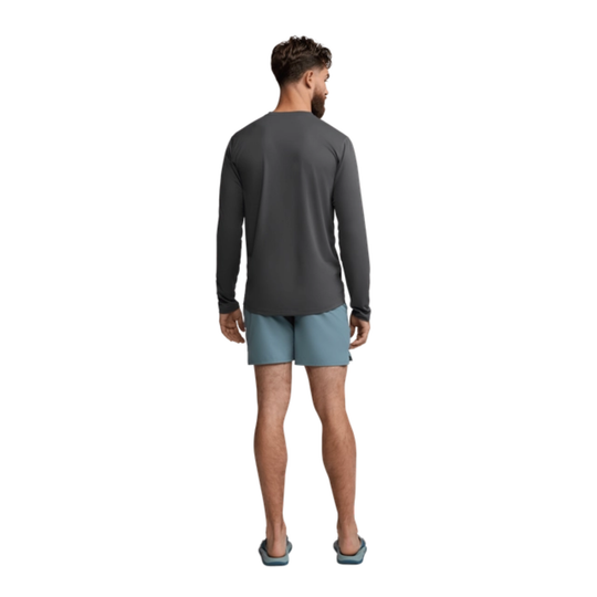 Man wearing a long-sleeve gray shirt and light blue shorts on a white background