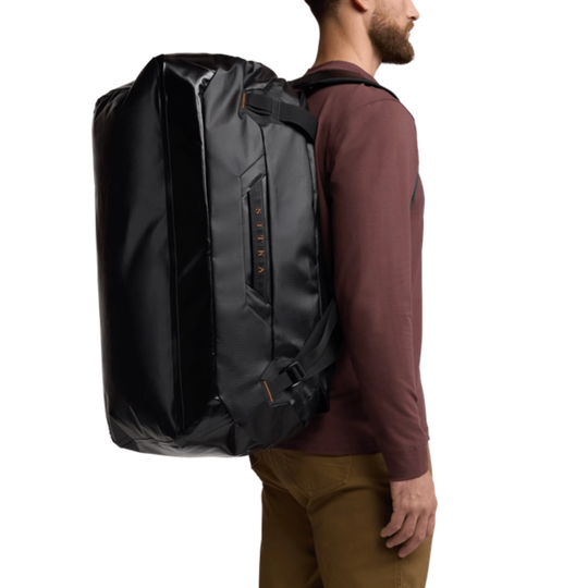 Person wearing a large black backpack on a white background