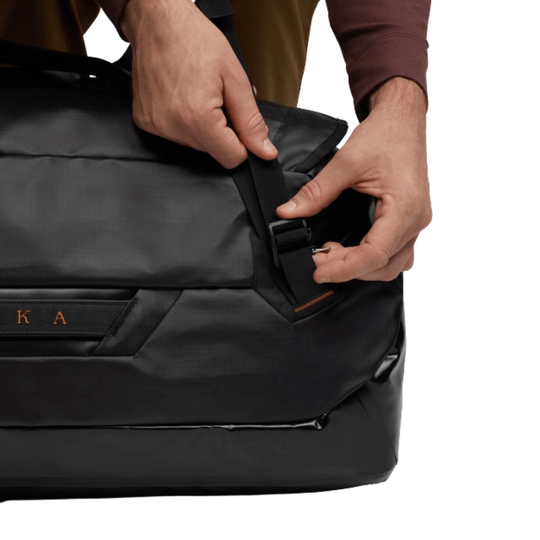 Person adjusting a black bag with a visible brand logo on a white background