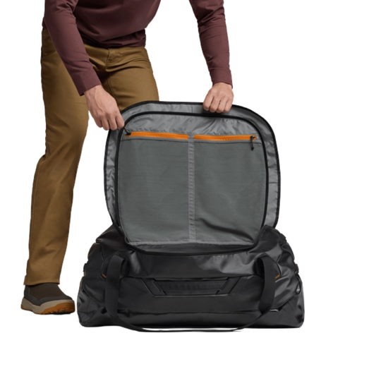 Person opening a large black backpack with a gray interior on a white background