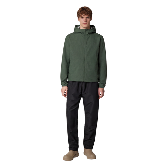 Person wearing a green raincoat and black pants on a white background