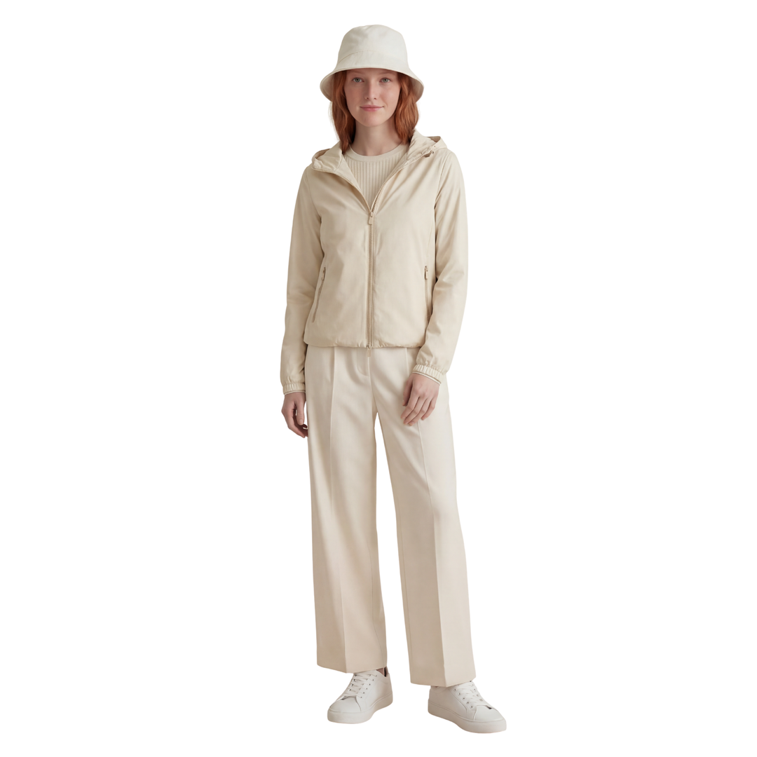 Person wearing a beige outfit with a matching hat on a white background