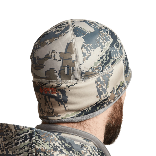 Camouflage beanie worn by a person on a white background