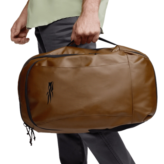 Brown duffel bag with a brand logo held by a person on a white background