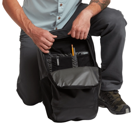 Person opening a black backpack with multiple compartments on a white background