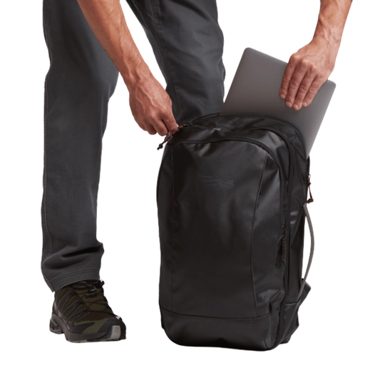 Person holding a black backpack with a laptop inside on a white background
