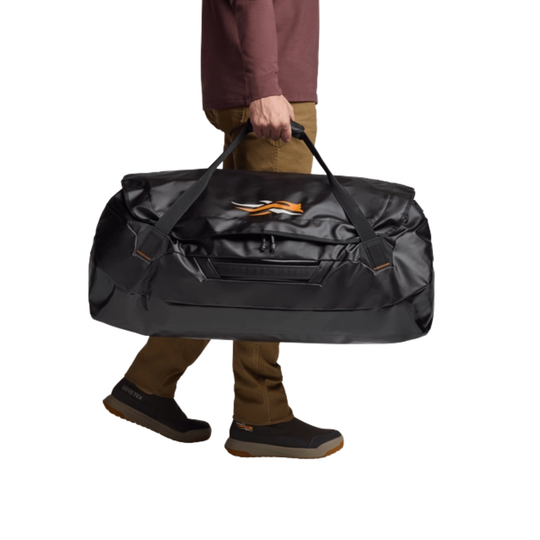 Person holding a large black duffel bag with an orange logo on a white background