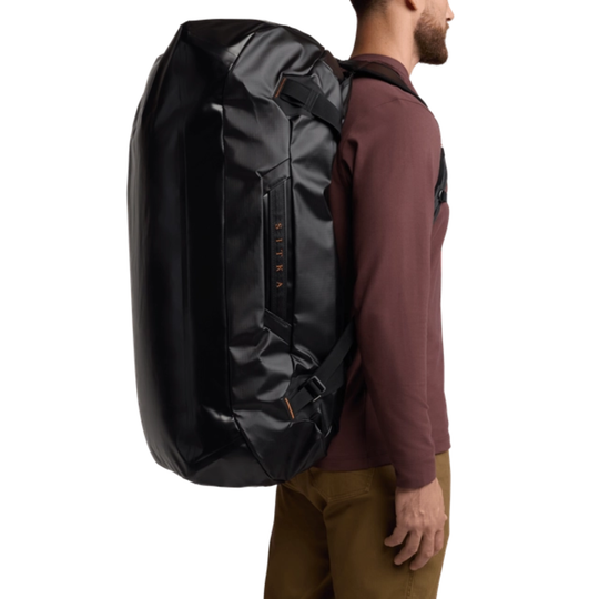 Person wearing a large black backpack on a white background