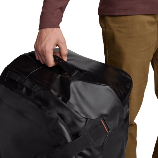 Person holding a black duffel bag with a white background