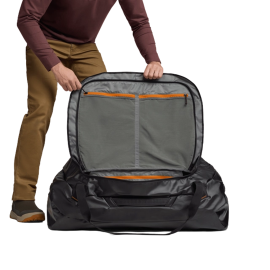 Person holding a large gray and black travel bag with orange accents on a white background