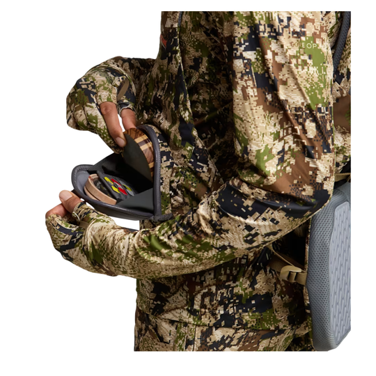 Person in camouflage gear holding a black device with colorful buttons.