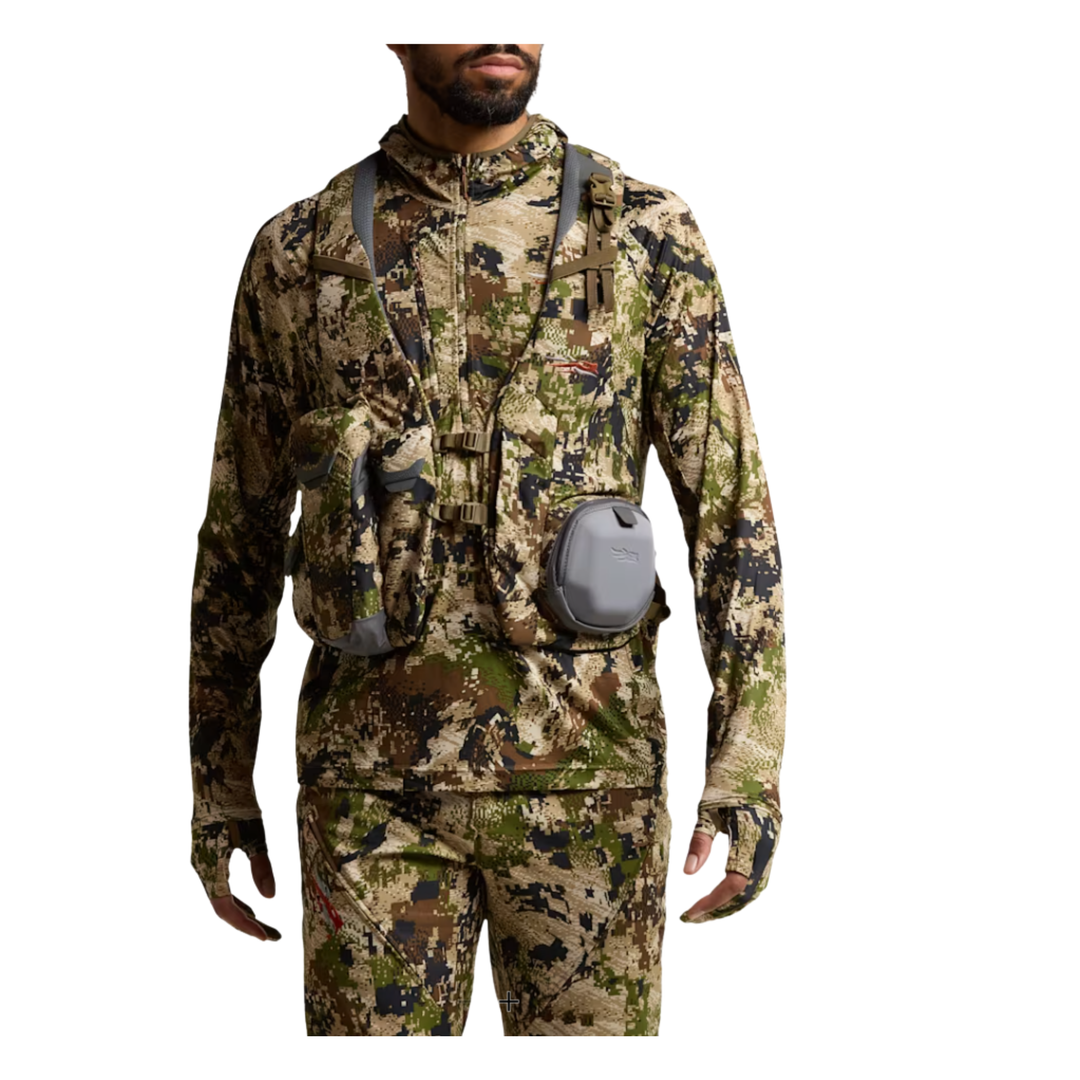 Person wearing full camouflage hunting gear with a white background