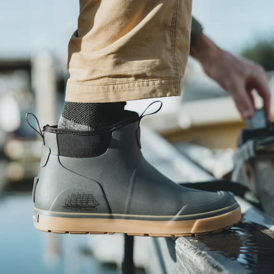 Person wearing a gray boot with a brand logo, standing on a dock.