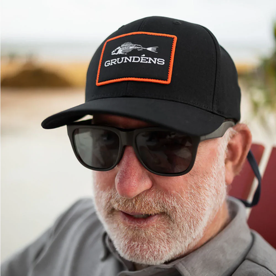 Man wearing a black cap with Grundéns logo and sunglasses outdoors