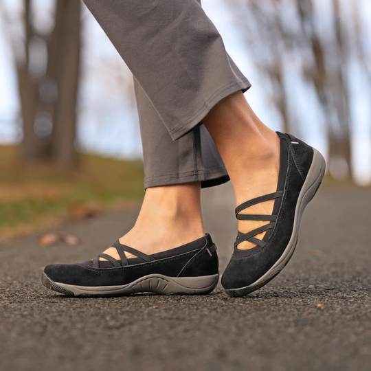 Black casual shoes worn outdoors on a blurred natural background