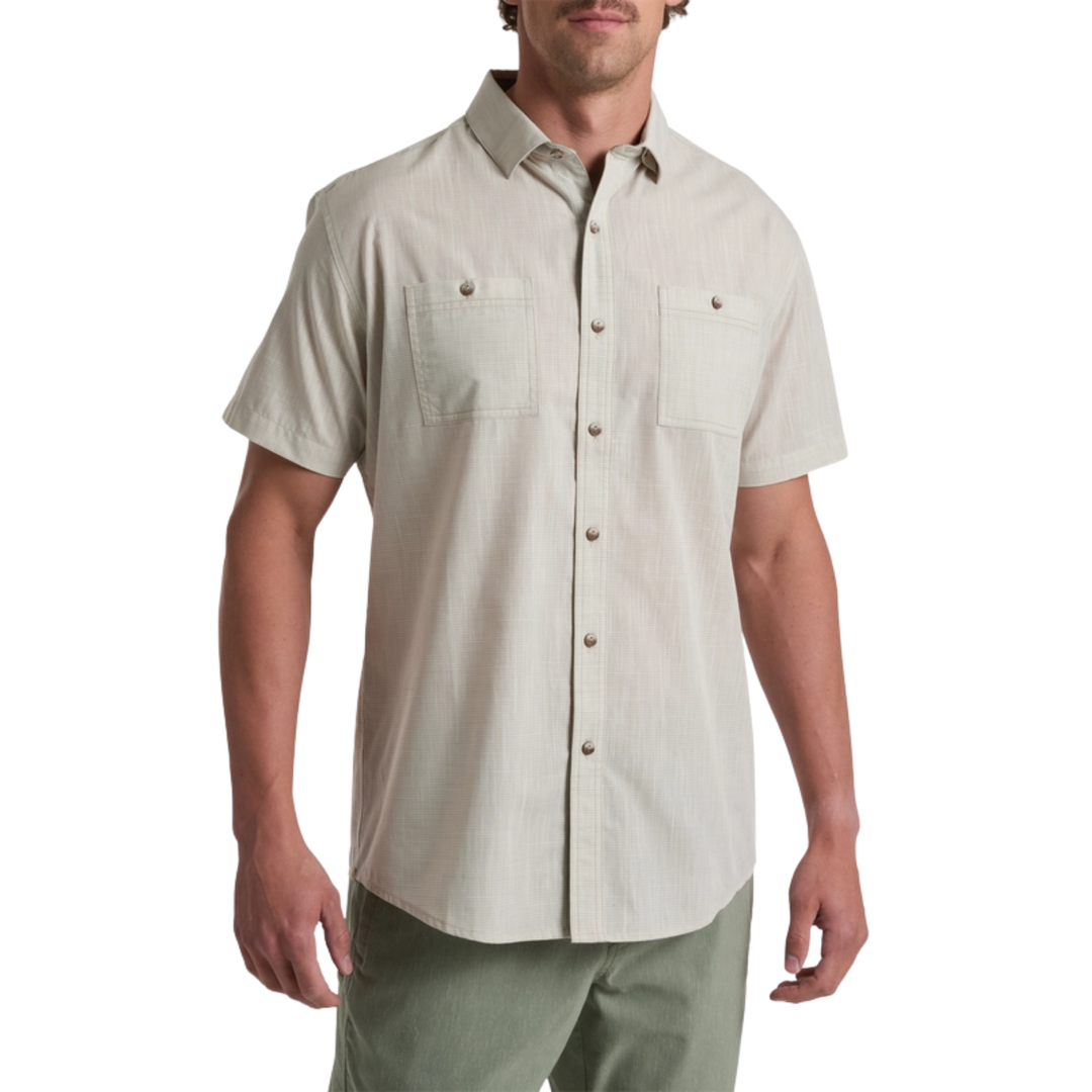 Man wearing a beige short-sleeve button-up shirt on a white background
