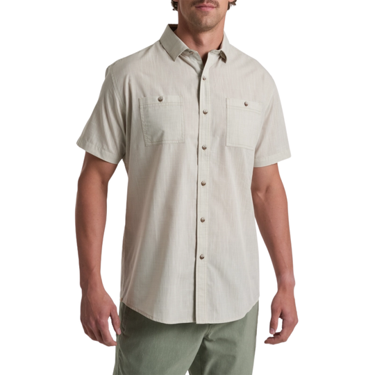 Man wearing a beige short-sleeve button-up shirt on a white background