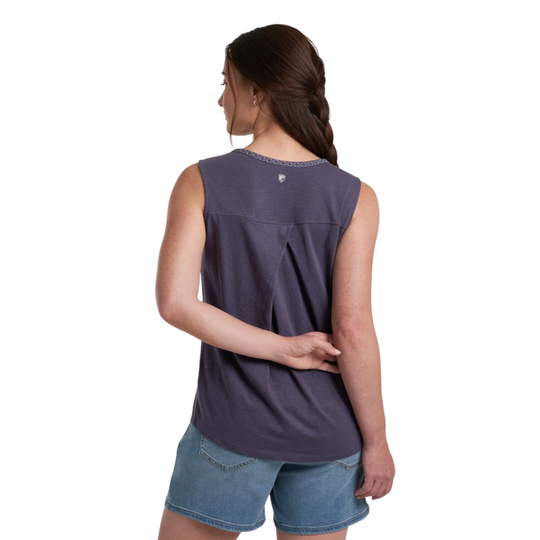 Woman wearing a sleeveless purple top and denim shorts on a white background