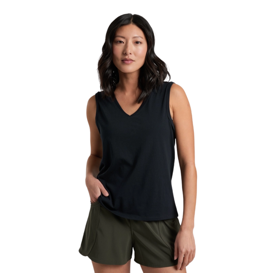 Woman wearing a black sleeveless top and green shorts on a white background