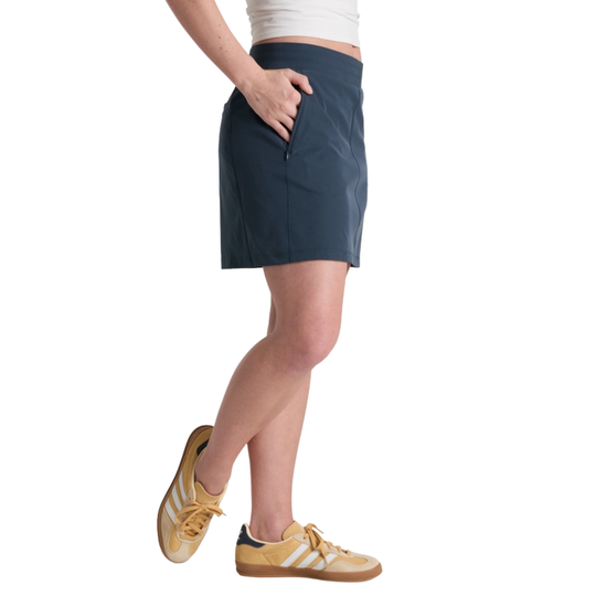 Person wearing a navy skirt with yellow sneakers on a white background