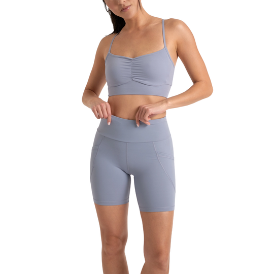 Woman wearing a gray sports bra and shorts set on a white background
