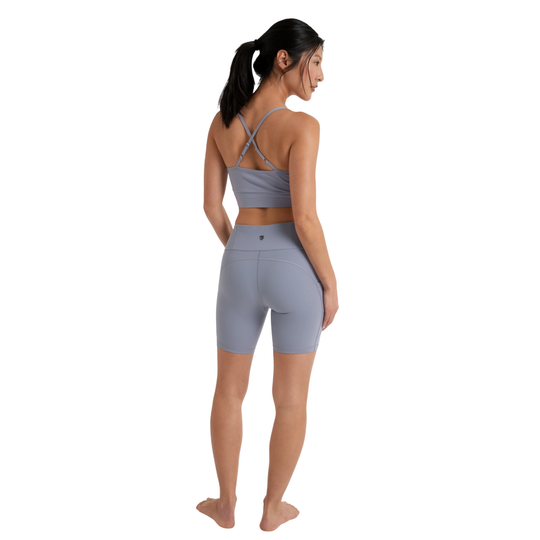 Woman wearing a gray sports bra and shorts on a white background