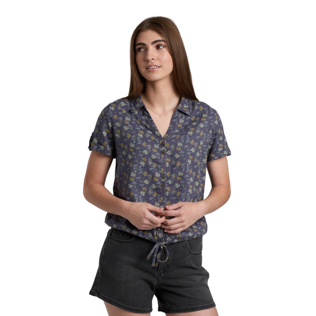 Woman wearing a patterned shirt and black shorts on a white background