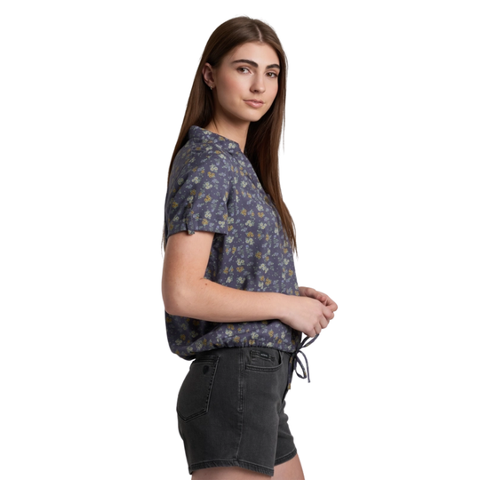 Woman wearing a patterned shirt and black shorts on a white background