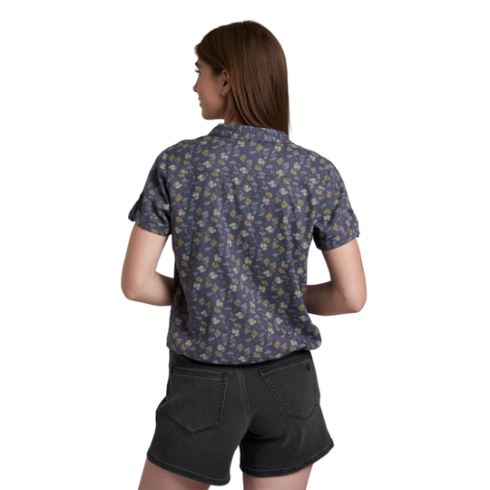 Woman wearing a patterned shirt and black shorts on a white background