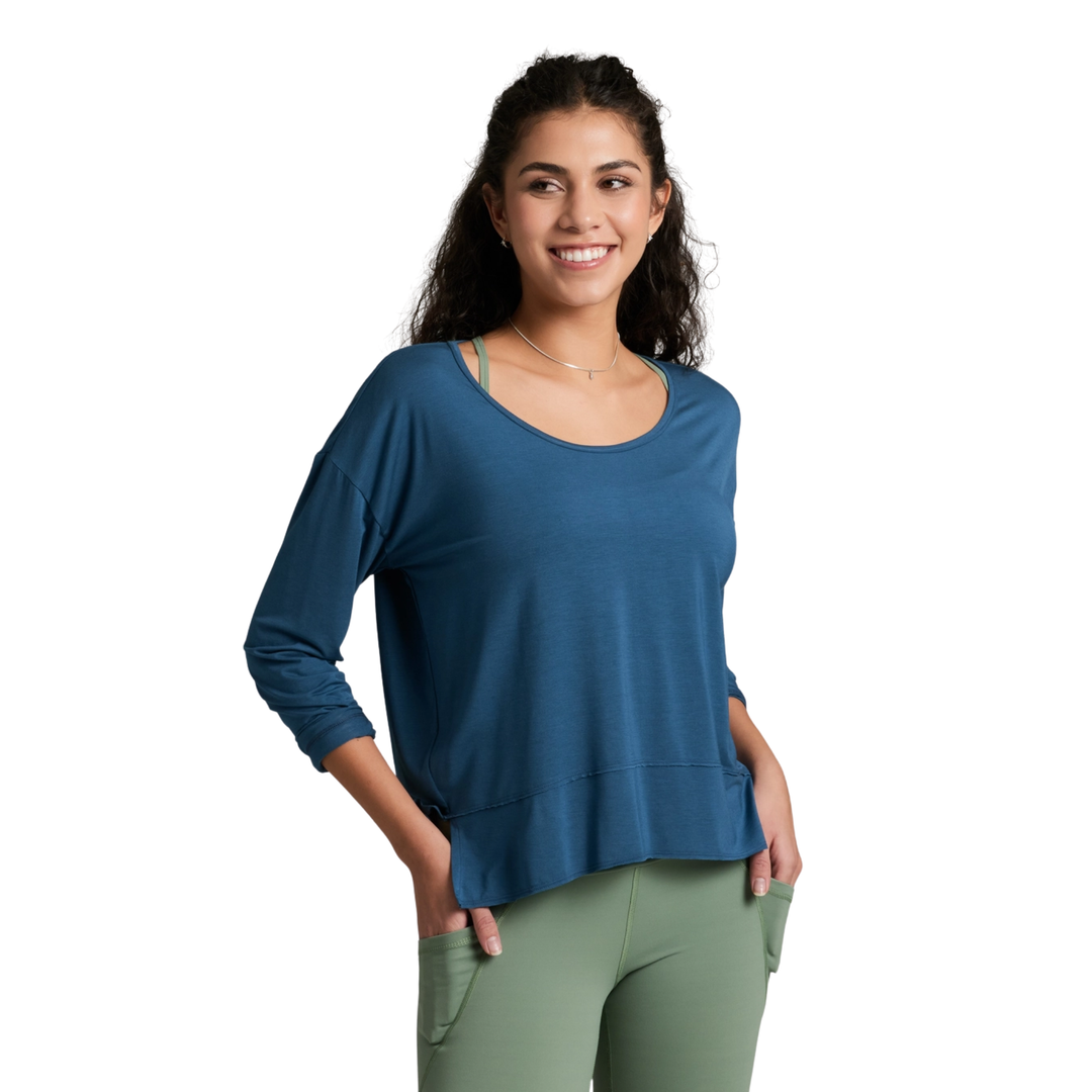 Woman wearing a blue long-sleeve top and green leggings on a white background