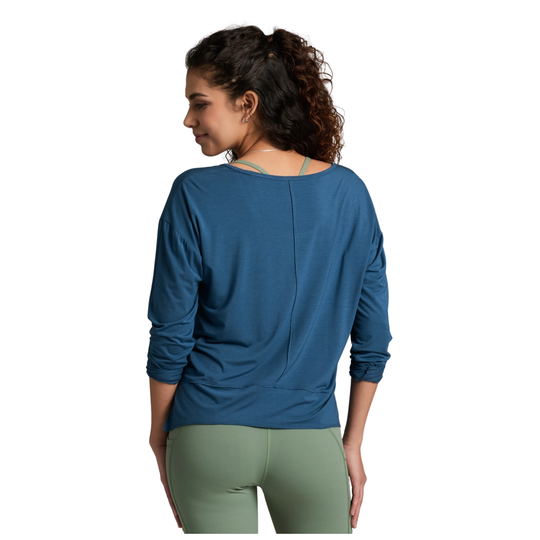 Woman wearing a blue long-sleeve top and green pants on a white background