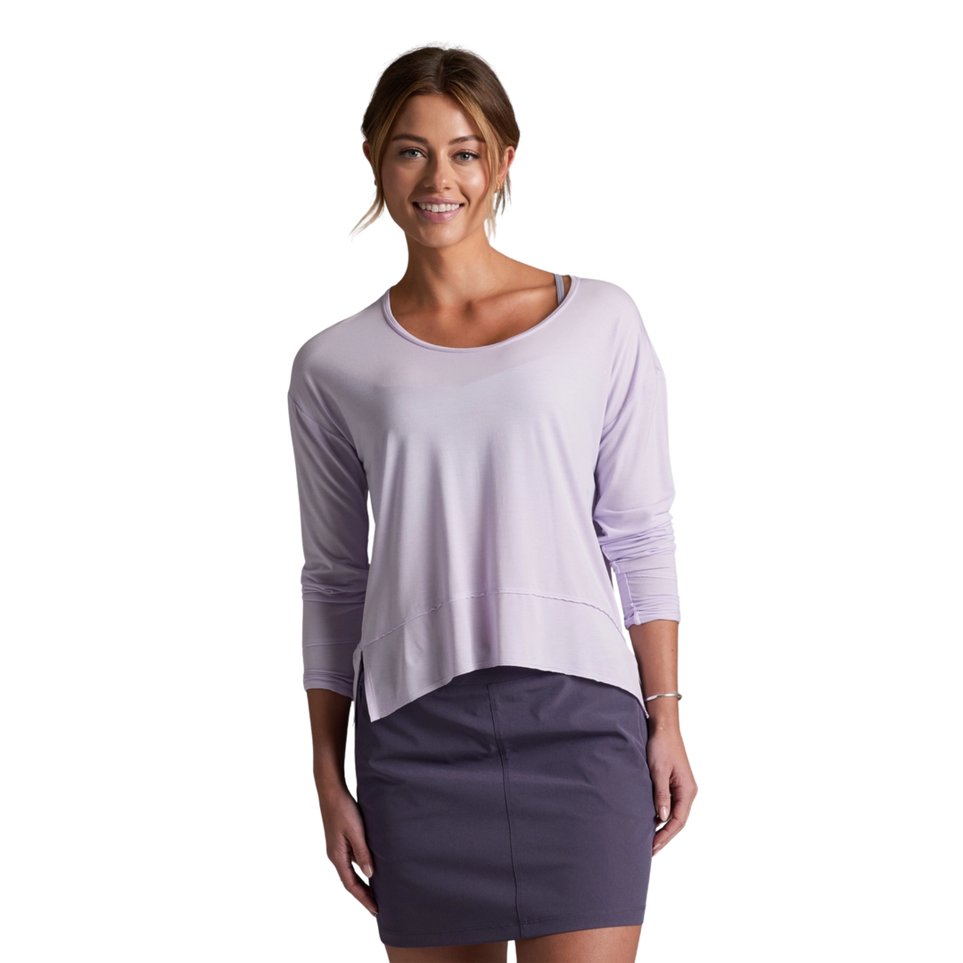Woman wearing a light purple long-sleeve top and dark gray skirt on a white background