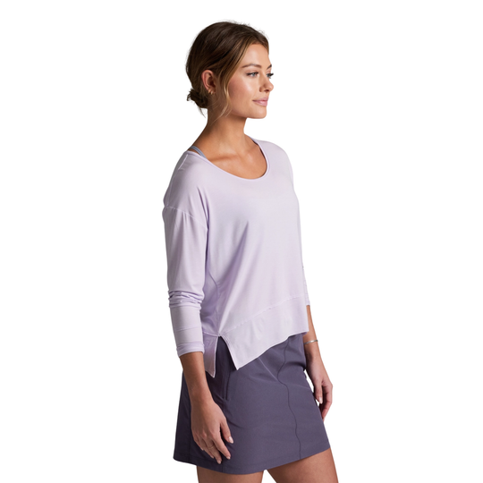 Woman wearing a light purple long-sleeve top and dark gray skirt on a white background