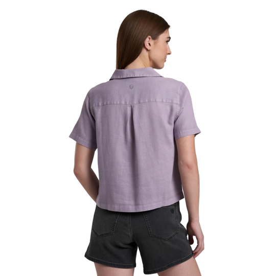 Woman wearing a purple short-sleeve shirt and black shorts on a white background