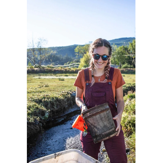 Woman holding a woven bag outdoors with a scenic background