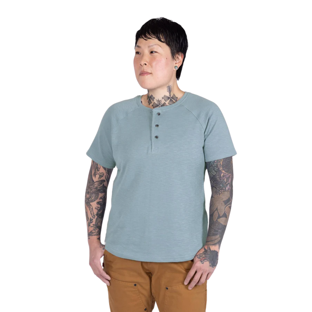 Person wearing a light blue henley shirt and brown pants on a white background