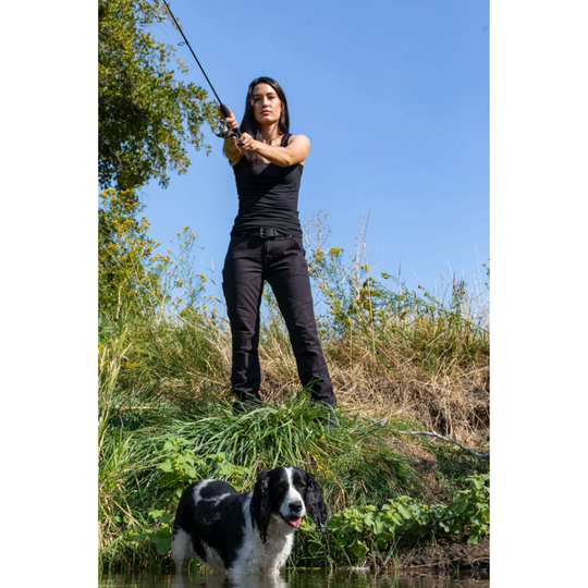 Woman fishing with a dog standing by the water