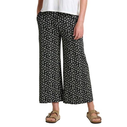 Person wearing black floral wide-leg pants on a white background