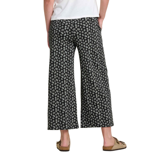 Person wearing black floral-patterned wide-leg pants on a white background
