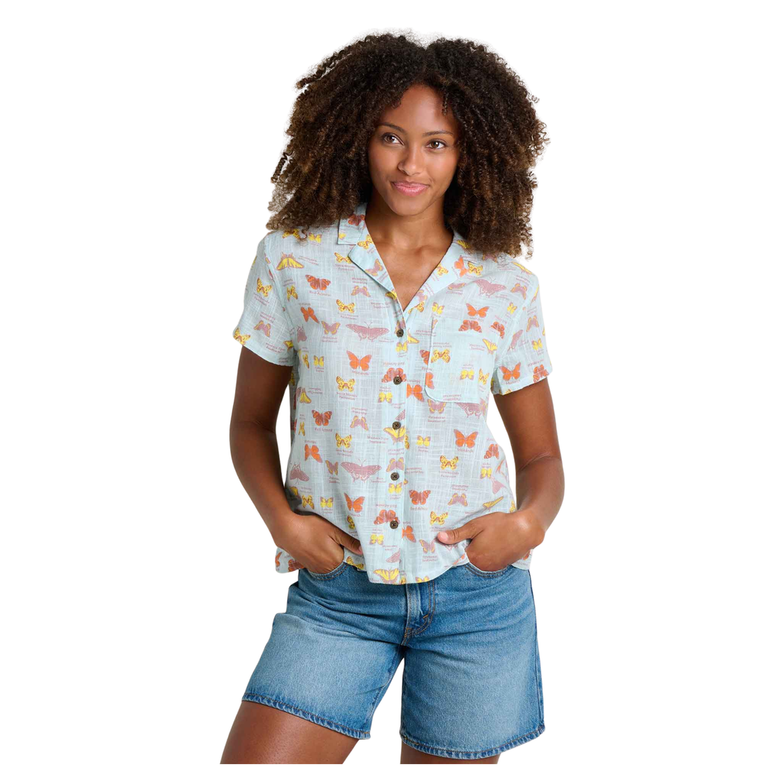 Woman wearing a light blue patterned shirt and denim shorts on a white background