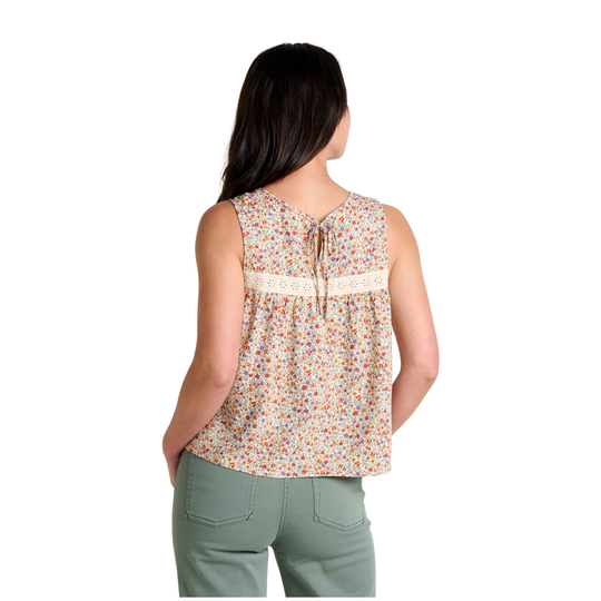 Woman wearing a sleeveless floral top and green pants on a white background