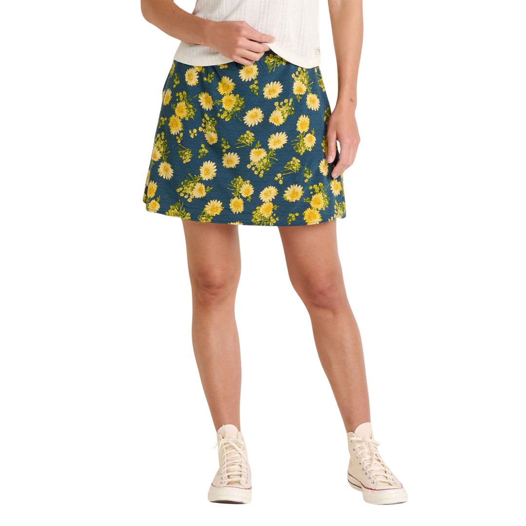 Person wearing a blue floral skirt with yellow flowers on a white background