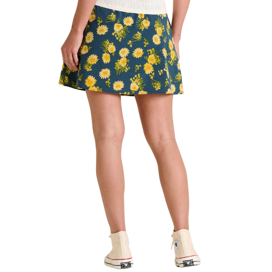 Person wearing a floral skirt with yellow flowers on a blue background