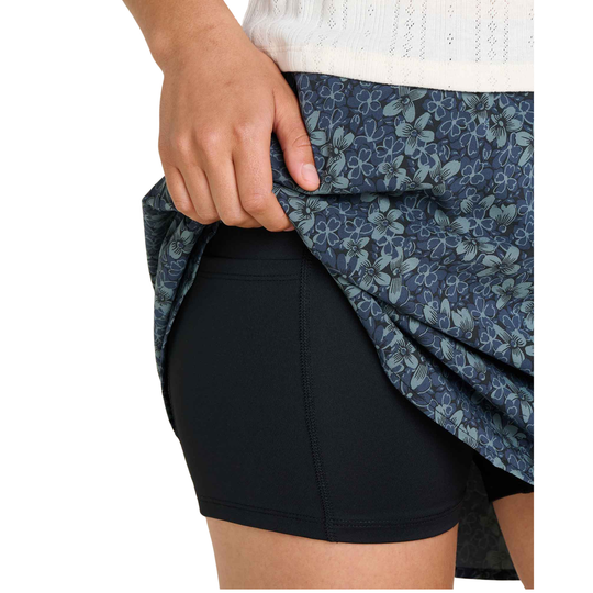Person wearing a black athletic skirt with a blue floral patterned shirt.