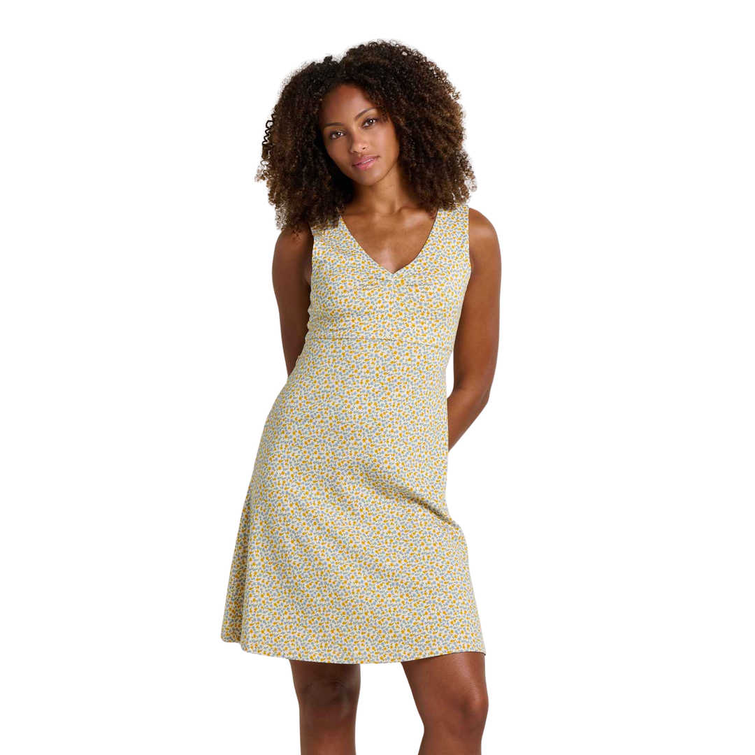 Woman wearing a sleeveless dress with a yellow floral pattern on a white background